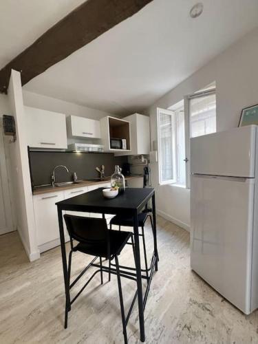 Il comprend une cuisine équipée d'une table noire et d'un réfrigérateur. dans l'établissement Studio Cozy Cœur de Ville, à Béziers