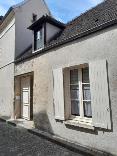 a white building with white shutters and a window at Gite La folie de Séraphine in Senlis