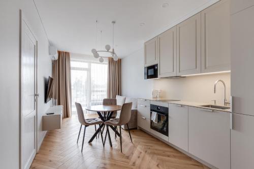 a kitchen with white cabinets and a table and chairs at Stylish Simplicity - 1BDR Cozy Stay in Vilnius in Kontverki