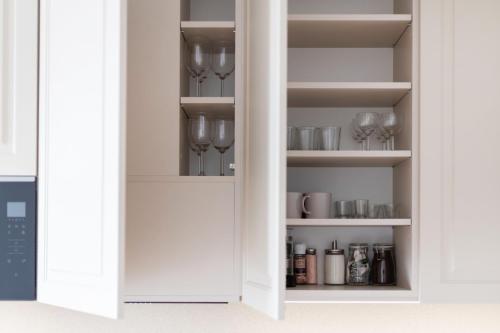 a white pantry with wine glasses on shelves at Stylish Simplicity - 1BDR Cozy Stay in Vilnius in Kontverki