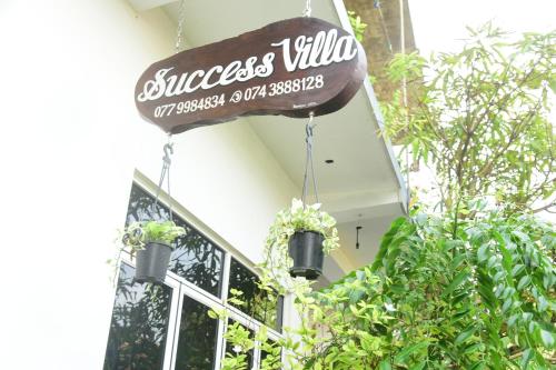 a sign on the side of a building with plants at Success Villa Hikkaduwa in Hikkaduwa