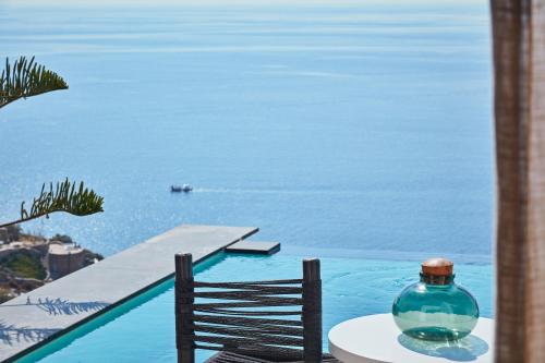 a glass bottle sitting on a table next to the water at Myconian Utopia Relais & Chateaux in Elia Beach