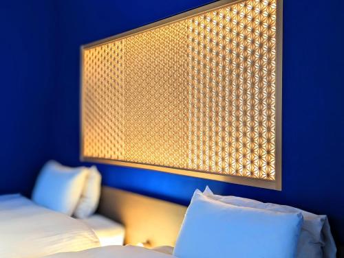 a bedroom with a blue wall with a bed and a lamp at ひがし茶屋街らしく金沢 Hotel Rashiku kanazawa in Kanazawa