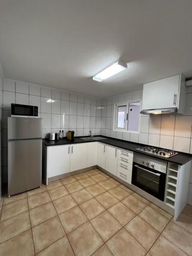 a kitchen with white appliances and black counter tops at Casa Pão - 5 mins from Machico centre with private parking in Machico