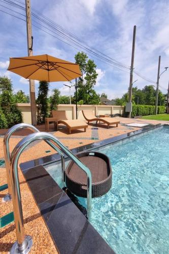 a swimming pool with an umbrella and chairs and a table at Siri Nakornpink Chiang Mai Hotel SHA Plus in Chiang Mai