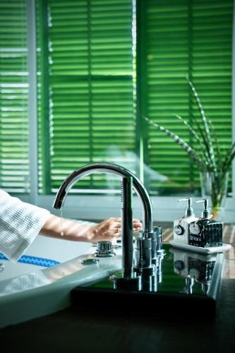 a person is washing their hands at a kitchen sink at A-Te Chumphon Hotel - SHA Plus in Chumphon