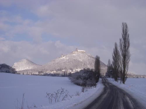 a snowy road with a mountain in the background at Apartmány u jezera Fami*** in Doksy