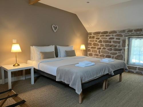 une chambre avec un grand lit et un mur en pierre dans l'établissement Gîtes Le Fer A Cheval Vassivière, à Royère-de-Vassivière