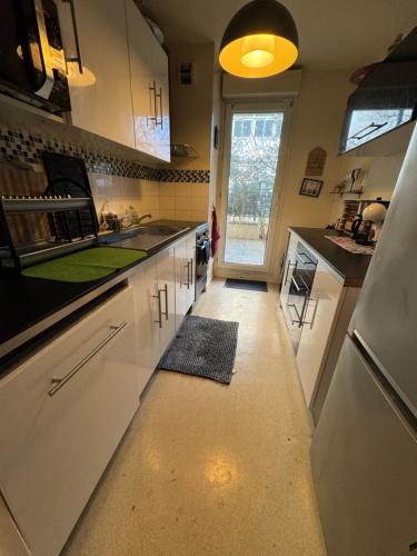 - une cuisine avec des placards blancs et un tapis vert au sol dans l'établissement proche paris la defense, à Clichy