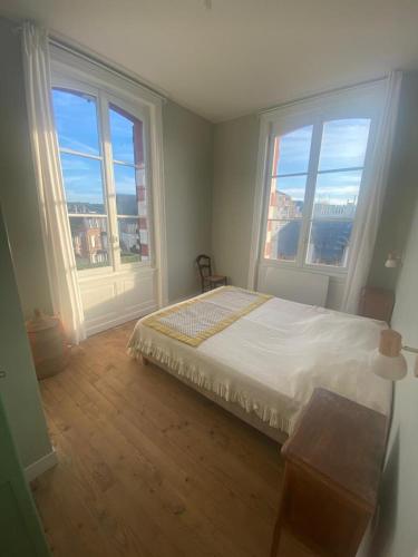 une chambre avec un lit et deux grandes fenêtres dans l'établissement Appartement, accès direct plage, vue imprenable face à la mer, à Villers-sur-Mer