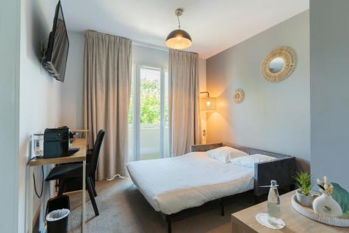 a bedroom with a bed and a desk with a computer at Best Western Hôtel Garden and Spa in La Baule