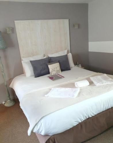 a large bed with white sheets and blue pillows at Logis Hôtel Restaurant l'Auberge Normande in Carentan