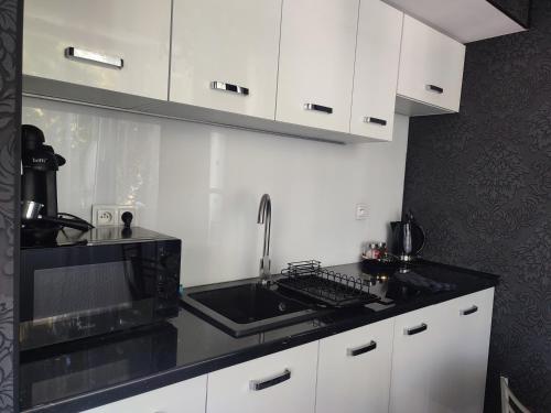 a kitchen with white cabinets and a sink and a microwave at Apartament Lux2 Konin NOCLEGI in Konin