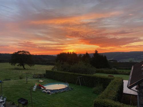 a sunset over a yard with a small pool at La chambre Cour'toise in Stoumont