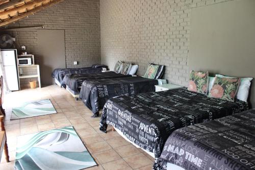 a room with four beds and a tiled floor at Kameelboom Lodge in Vryburg