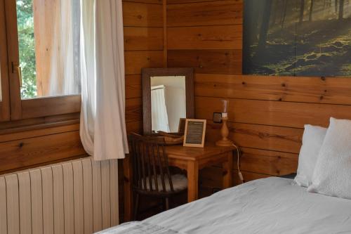 a bedroom with a bed and a desk with a mirror at Minds & Mountains Eco Lodge in La Molina
