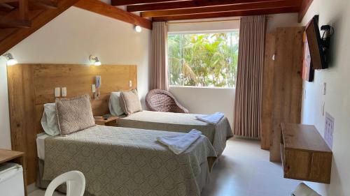 a bedroom with a bed and a couch and a window at Kaliman Pousada in Ubatuba