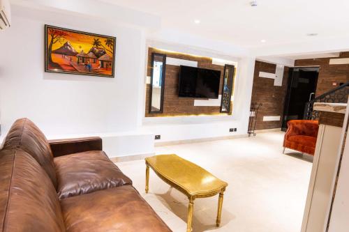 a living room with a leather couch and a table at Yellow Trumpet Residence Asokoro in Asokoro