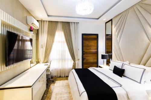 a bedroom with a large bed and a television at Yellow Trumpet Residence Asokoro in Asokoro