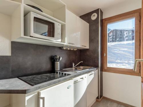 une cuisine avec un évier et un micro-ondes dans l'établissement Charmant appart. skis aux pieds, terrasse sud, central, 4 pers, TV, parking, casier à ski - FR-1-351-148, à La Plagne Tarentaise