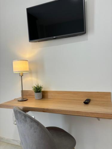 a television on a wall with a chair and a lamp at Hotel Lince in Aznalcázar