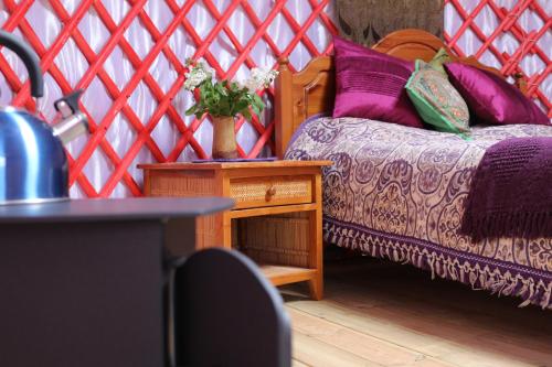 a bedroom with a bed and a table with a vase of flowers at Ettrick Valley Yurts in Yarrow