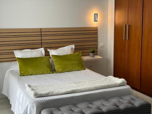 a bedroom with a bed with green pillows at Hotel Lince in Aznalcázar