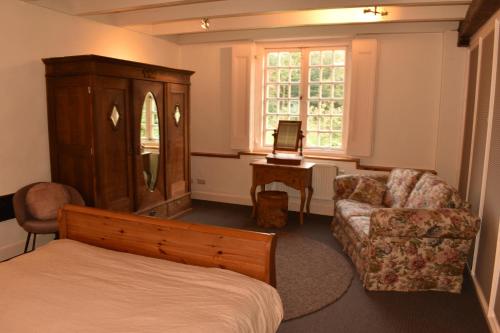a bedroom with a bed and a chair and a dresser at De Orangerie in Loenen