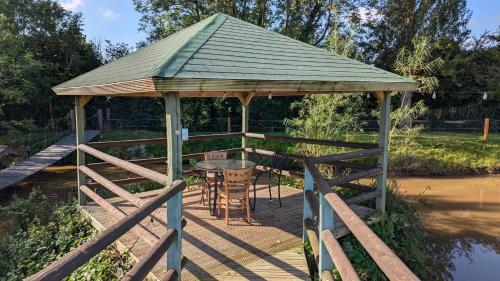 a gazebo with a table and chairs next to a river at Sunset Retreats The Anna Mae in Worcester