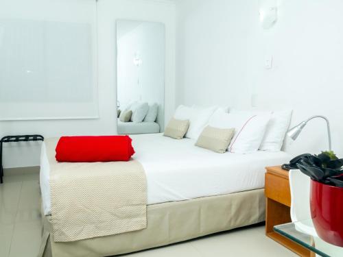 a white bedroom with a red pillow on a bed at Zalmedina Hotel in Cartagena de Indias