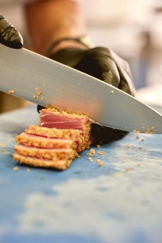 a person is cutting a piece of food with a knife at Hotel Saraceno Resort with Private Beach in Milano Marittima