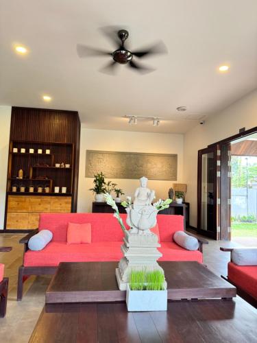 a living room with red couches and a ceiling fan at Mealy Villa in Phumi Ta Phul