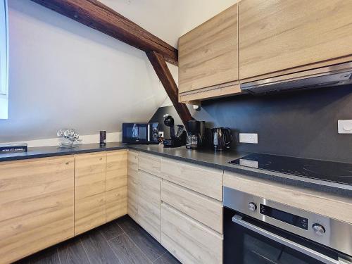 une cuisine avec des armoires en bois et un four à plaques de cuisson dans l'établissement Le NID DE CIGOGNE - Calme - Neuf - CLIMATISATION - Haut de gamme - Dernier étage, à Bernardswiller