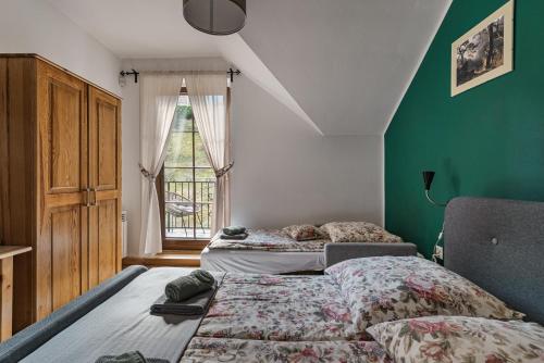 a bedroom with two beds and a green wall at Osada Pienińska in Krościenko