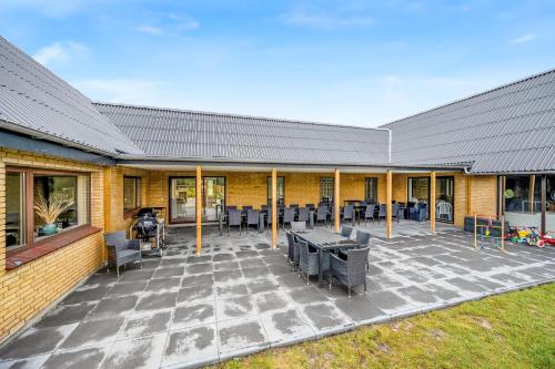 a patio with tables and chairs in front of a building at Large 30-Person Holiday Home With Pool And Spacious Activity Room - 5000 in Engesvang