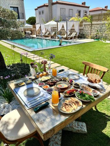 een picknicktafel met eten en drinken naast een zwembad bij Zaena Hotel Alaçatı in Alacati