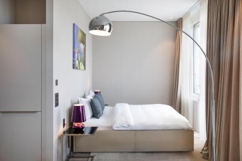 a bedroom with a bed with a floor lamp at VISIONAPARTMENTS St Gallen - contactless check-in in St. Gallen