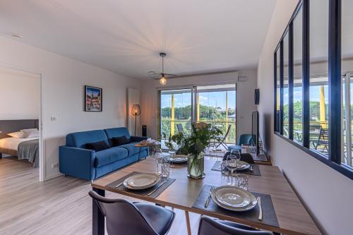 un salon avec une table et un canapé bleu dans l'établissement Les rives de la Marle - Appt avec parking couvert, à Vannes