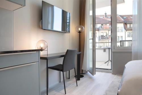 a room with a desk and a bed and a window at VISIONAPARTMENTS St Gallen - contactless check-in in St. Gallen