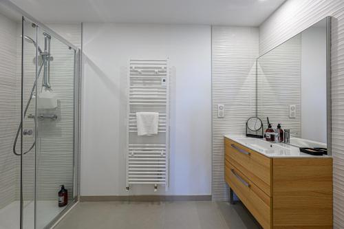 une salle de bain avec un lavabo et une douche en verre dans l'établissement Les rives de la Marle - Appt avec parking couvert, à Vannes