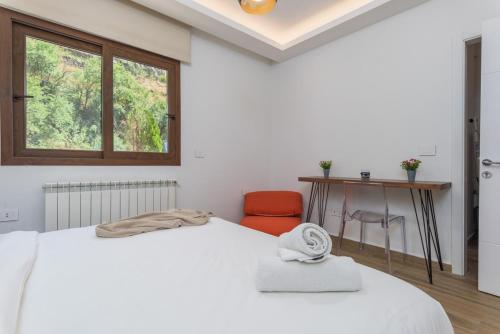a white bedroom with a bed and a desk and a window at Vantage - 2 BR Apt by The Valley in Kfardebian in ‘Ayn Barq