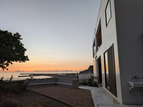 a building with a view of the ocean at sunset at mahaloha house 新築ビーチフロント ペット同伴プラン有 ｍax8名 BBQ 海歩1分 アイランドキッチン 大型プロジェクタ 床暖房 オーシャンビューバス in Isumi