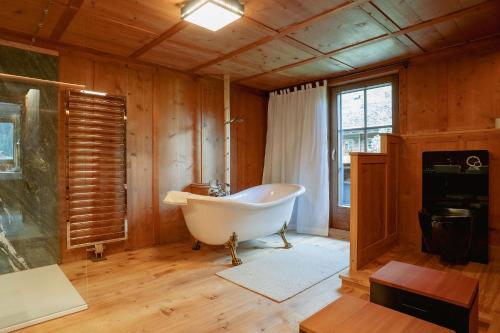 a bathroom with a tub in a room with wooden walls at Der Gannerhof in Innervillgraten