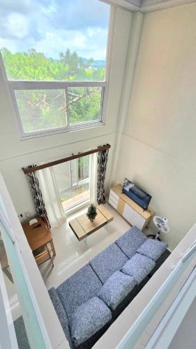 Una sala de estar con un sofá y una ventana grande. en GRAND VIEW BAGUIO CONDO TRANSIENT by DEI GRATIA, en Baguio