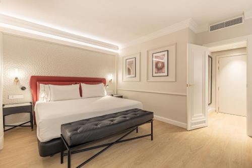 a bedroom with a large bed with a bench in it at Eurostars San Antón in Granada