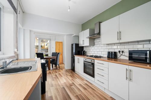 a kitchen with white cabinets and a wooden floor at The Castle - Grimsby/Cleethorpes perfect for Contractors in Grimsby