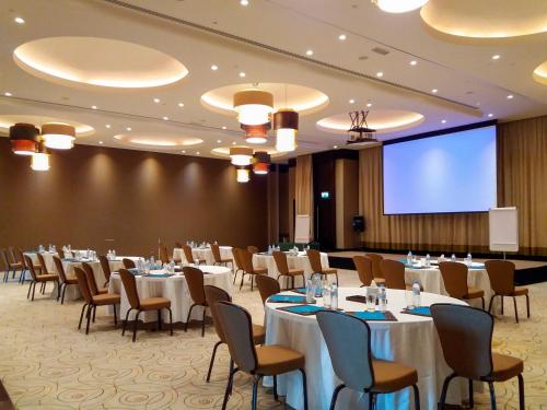 a conference room with tables and chairs and a projection screen at Meliá Desert Palm Member of Meliá Collection in Dubai