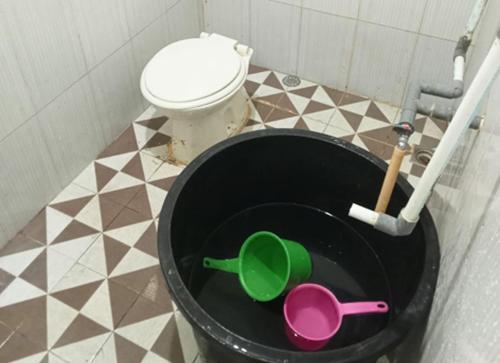 a bathroom with a toilet and a black bucket at Benatsya Homestay in Si Antar
