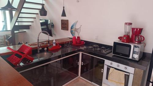 a kitchen with a counter with a microwave and a sink at Casa Duas Torres in Búzios