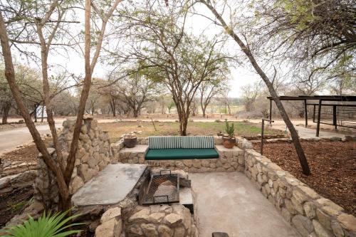 a stone wall with a bench and a table at Foxy Crocodile Bush Lodge & Kruger Safari's - No Loadshedding in Marloth Park